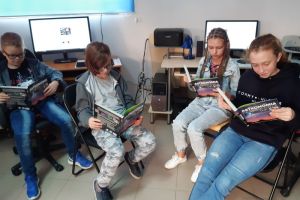 uczniowie przy komputerach czytający książki